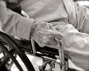 Black and white image of an elderly man’s hand holding a cane for support.